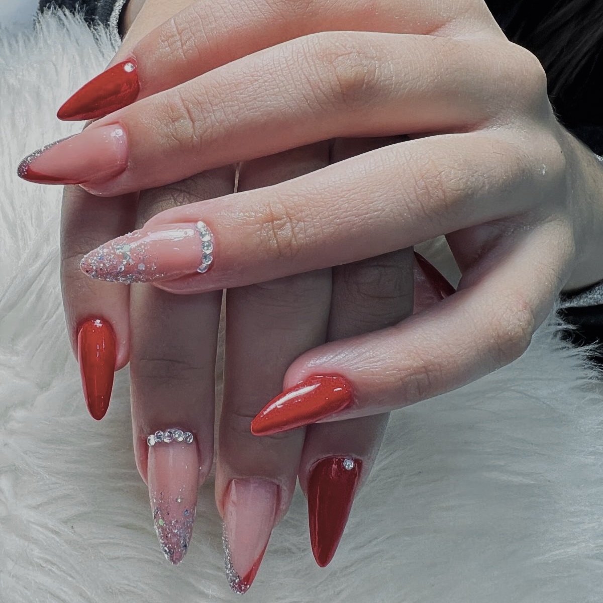 Nail art vermelha com brilho e aplicações discretas